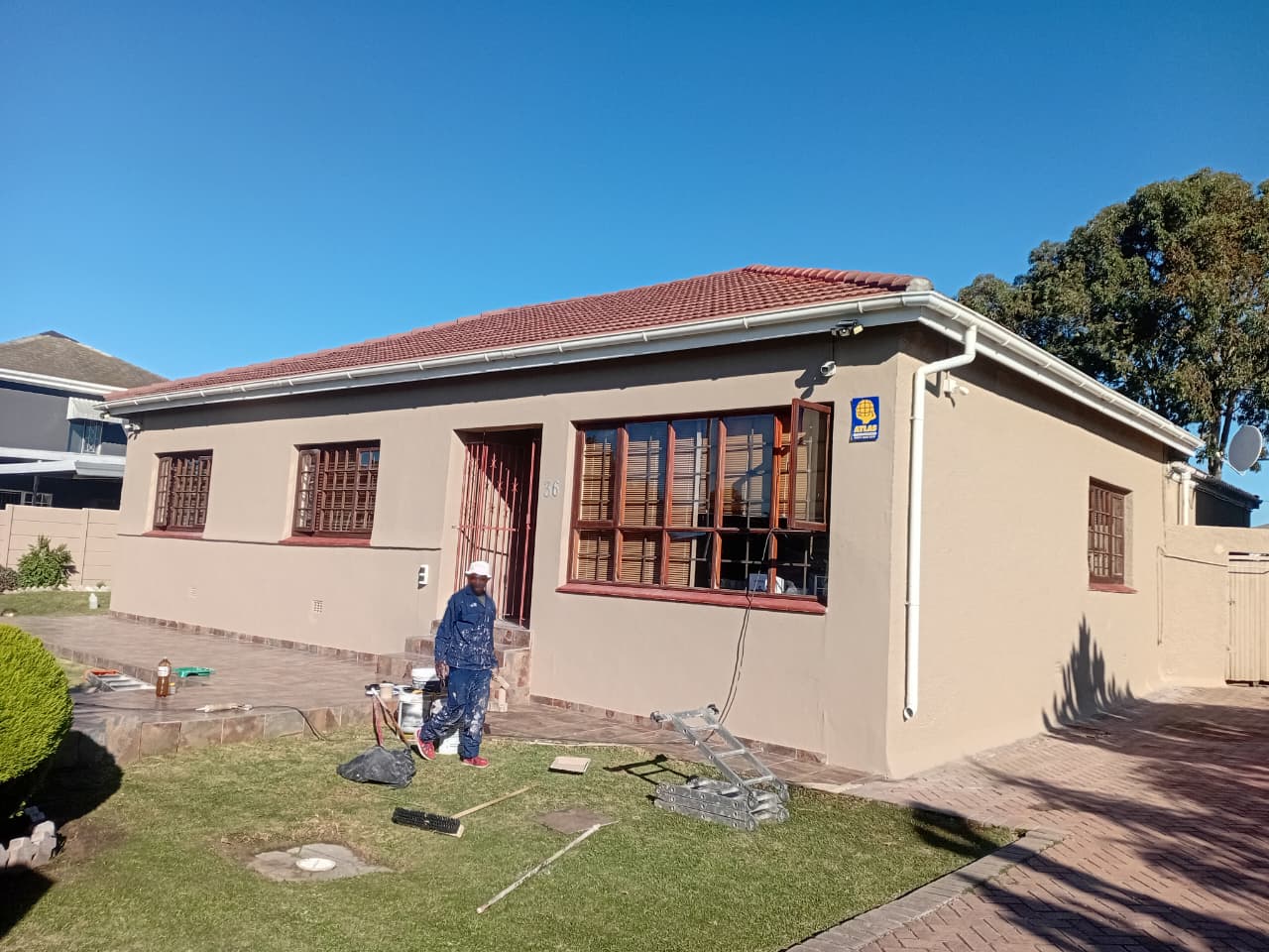 After: Exterior house painting Port Elizabeth — freshly painted cream finish, burgundy window frames, red tile roof