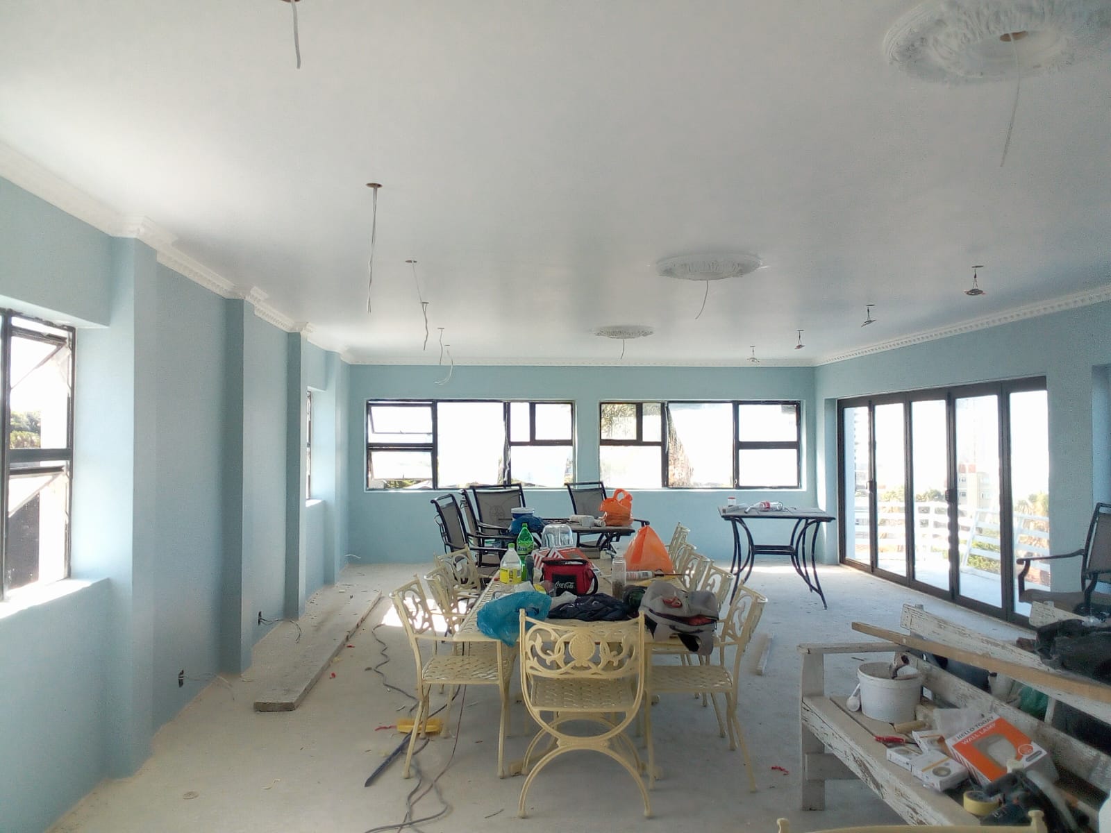 After: House renovation Gqeberha — wide room transformed with light blue walls, white ceiling and pendant lights