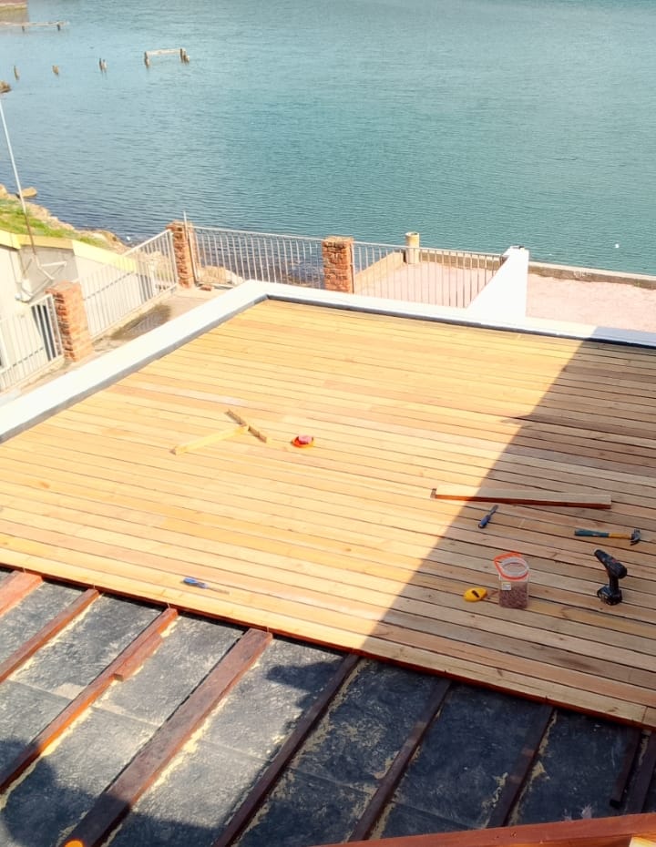 Before: Wooden decking Port Elizabeth — fresh pine boards laid but unstained on rooftop, lagoon view behind